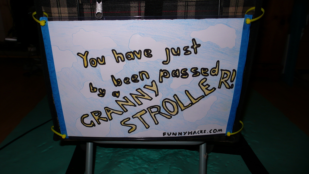 A sign on the back of the granny stroller that reads: You have just been passed by a granny stroller.